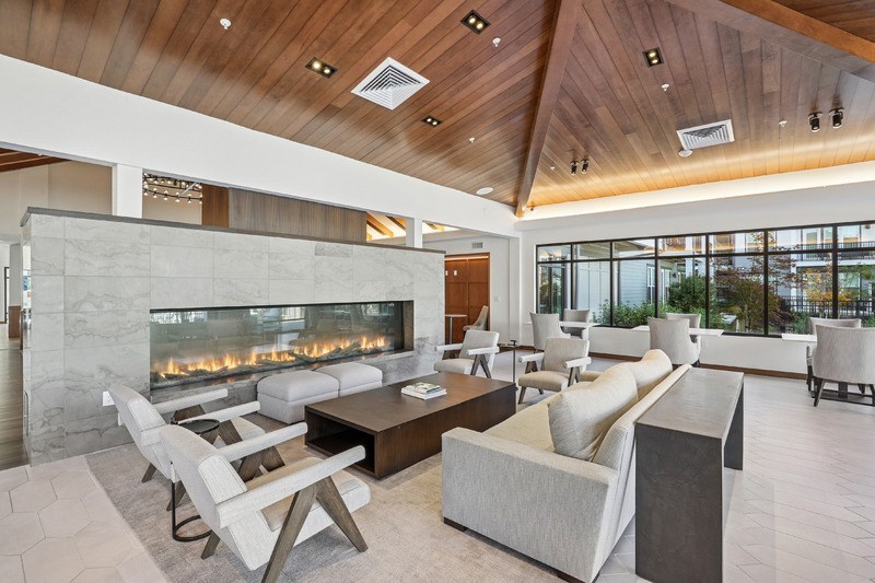 A modern living room with a stone fireplace and wooden ceiling.