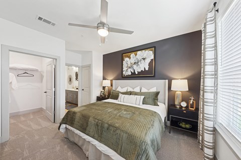 A bedroom with a bed, nightstand, and a painting on the wall.