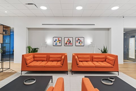 Two orange couches in a room with a grey coffee table.
