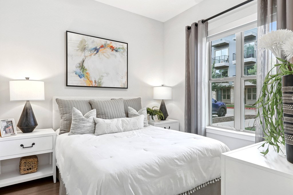 A bedroom with a large bed, a white nightstand, and a framed picture on the wall.