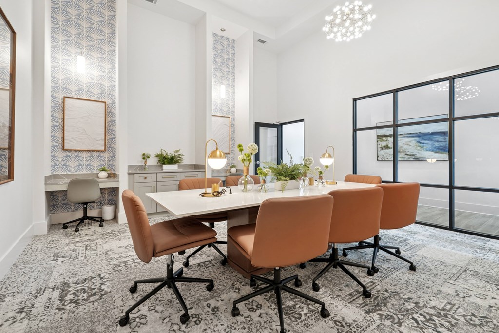 A conference room with a long table surrounded by orange chairs.