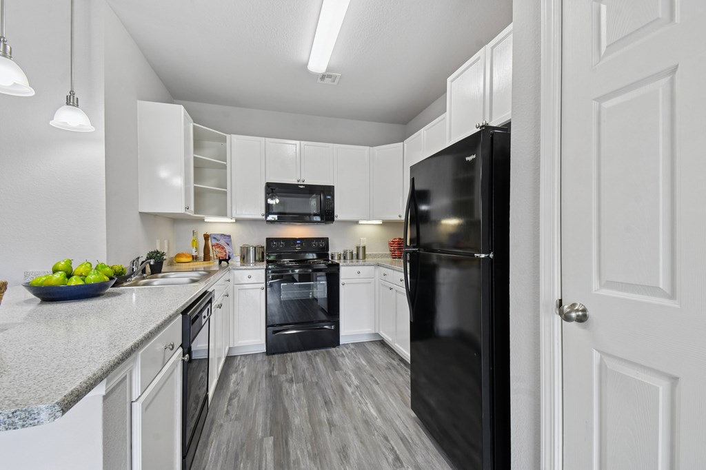 A black refrigerator is in a white kitchen.