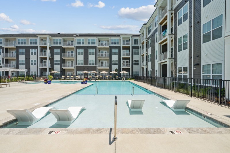 A large swimming pool in front of apartment buildings.