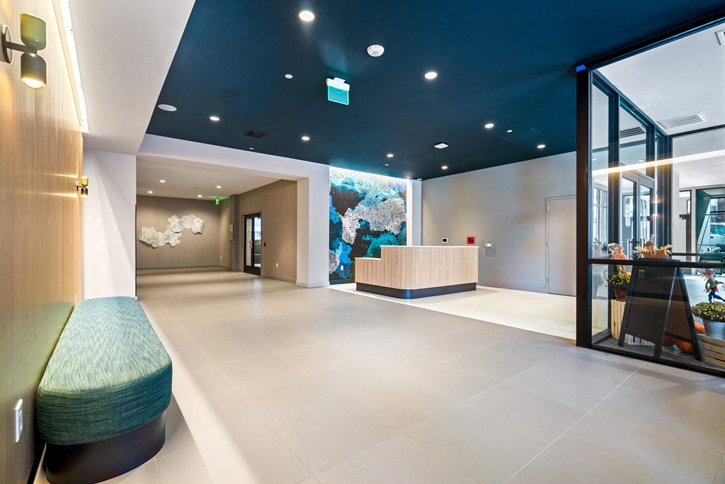 a lobby with a reception desk and a blue ceiling with a wall mural