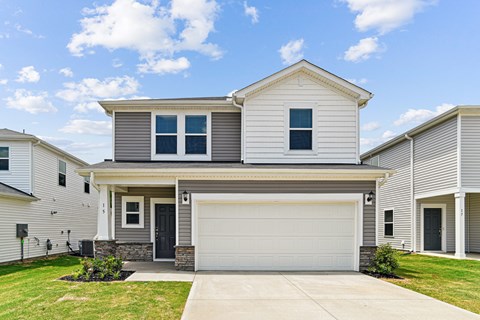 A two-story house with a garage door and a front porch.