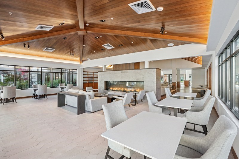 A modern dining room with a fireplace and a view of the trees outside.