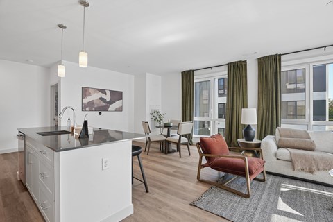 A modern kitchen with a white island and a dining area with a white couch and chairs.