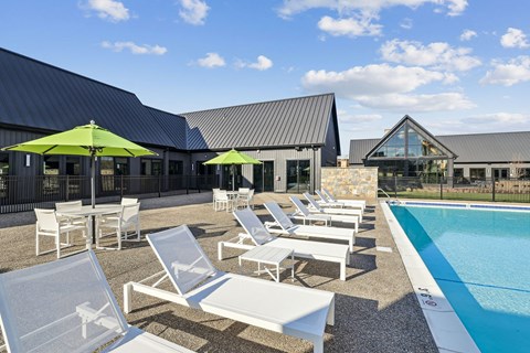 A pool area with sun loungers and umbrellas.