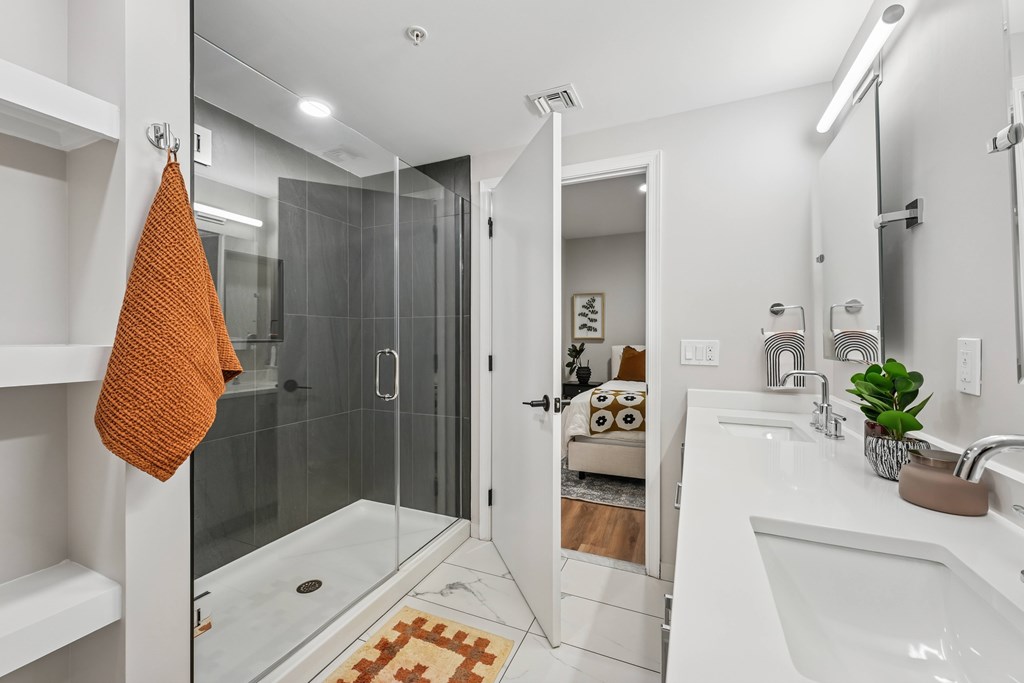 A bathroom with a white sink and a glass shower stall.
