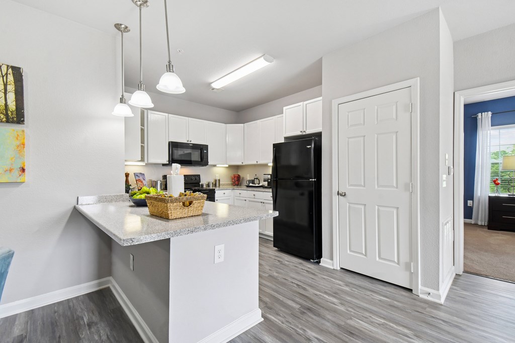 A kitchen with a black fridge and white cabinets.