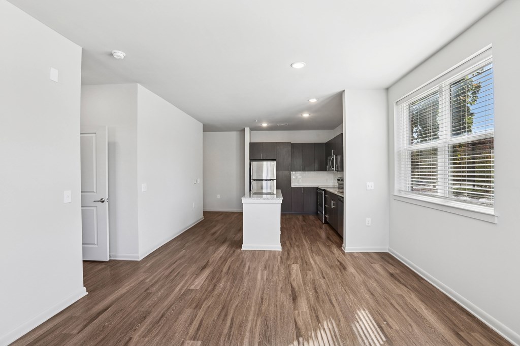A spacious room with wooden flooring and white walls.