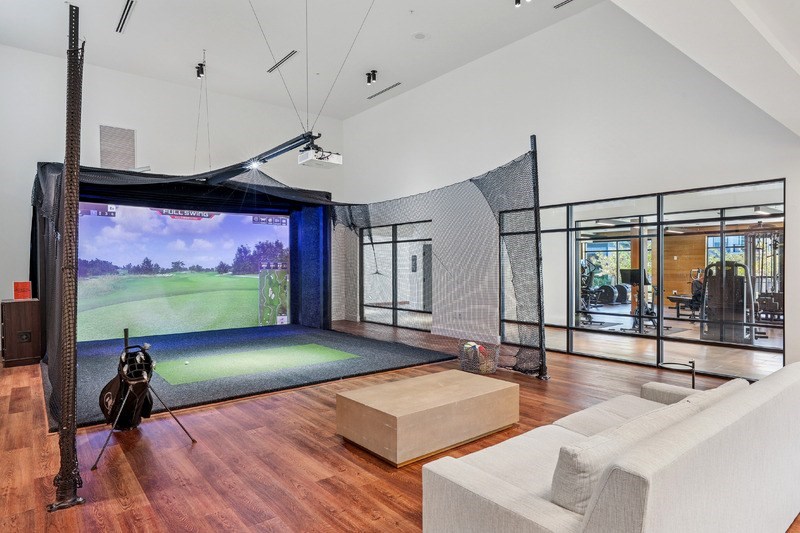 A room with a golf simulator and a couch.