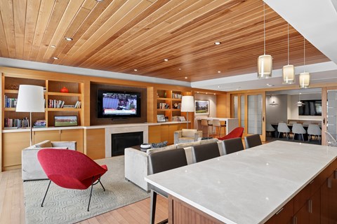 A modern living room with a red chair and a wooden ceiling.
