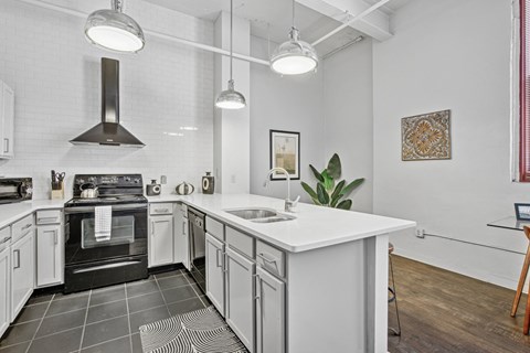 A modern kitchen with a black stove top oven and white cabinets.