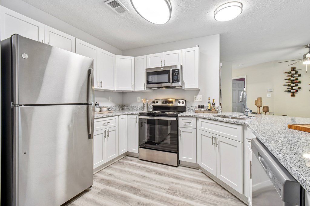 A kitchen with a refrigerator, oven, and microwave.
