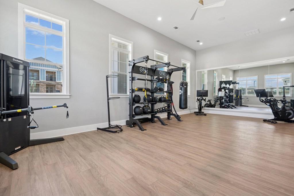 A spacious gym with wooden floors and various exercise equipment.