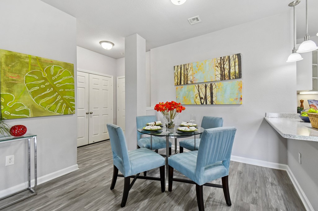 A dining room with a table set for two and a painting on the wall.