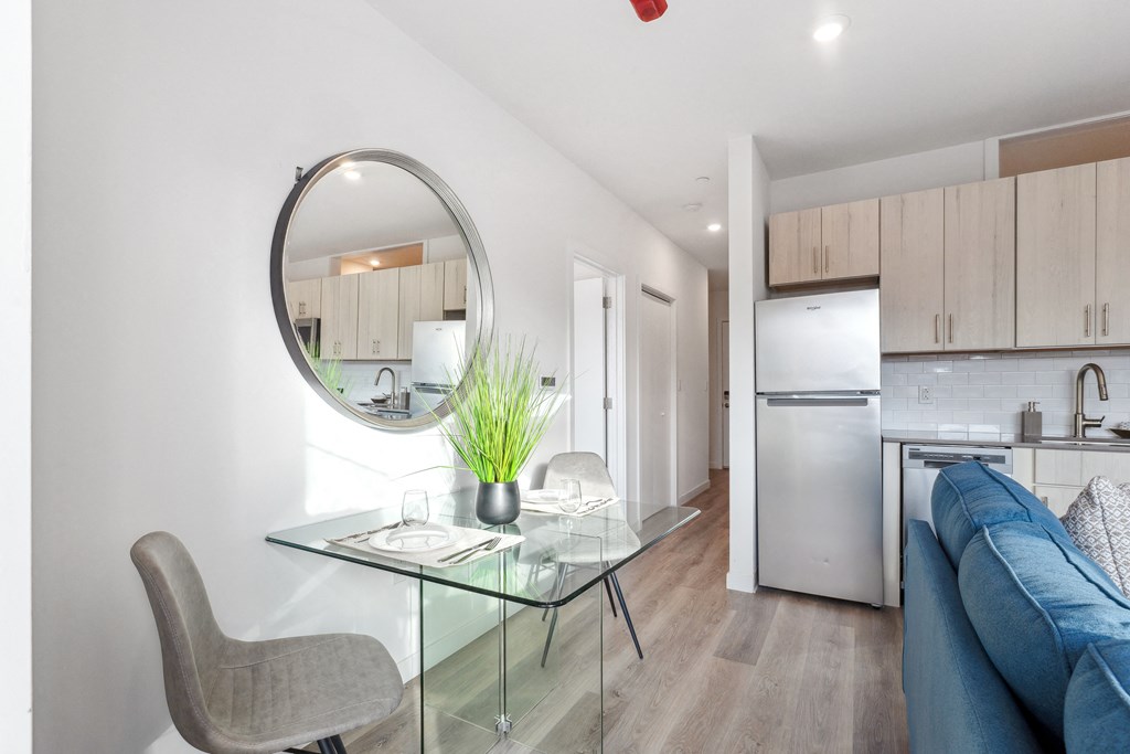 a living room with a glass table and a kitchen