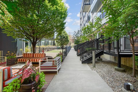 A concrete walkway with a metal railing on the right side and a tree with green leaves on the left side.