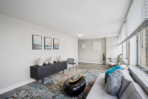 A living room with a grey couch, a black table, and a painting on the wall.