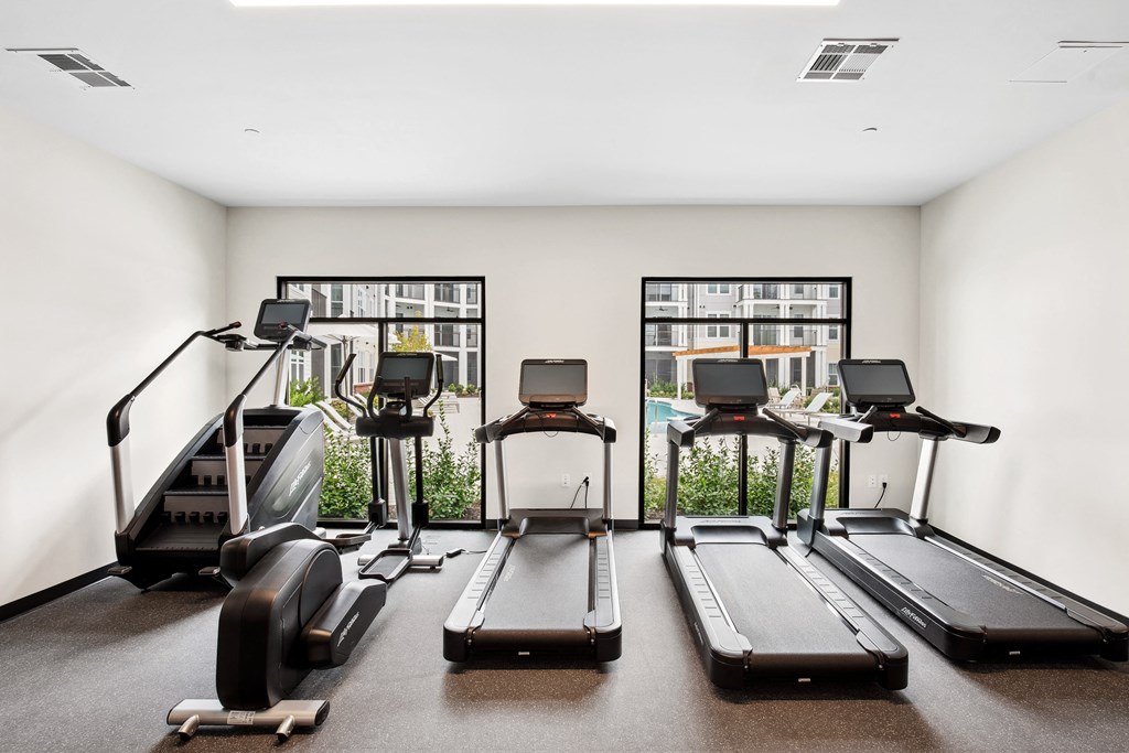 four treadmills in a fitness room with windows