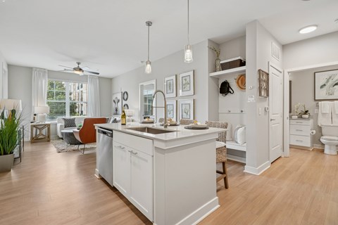 A kitchen with a white island and a dining area with a table and chairs.