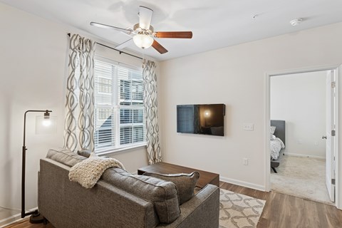 A living room with a grey couch and a ceiling fan.