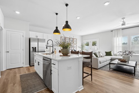 A modern kitchen with white cabinets and a wooden floor.
