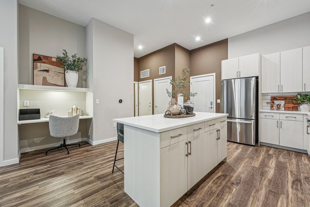 a kitchen with white cabinets and a white counter top and a stainless steel refrigerator