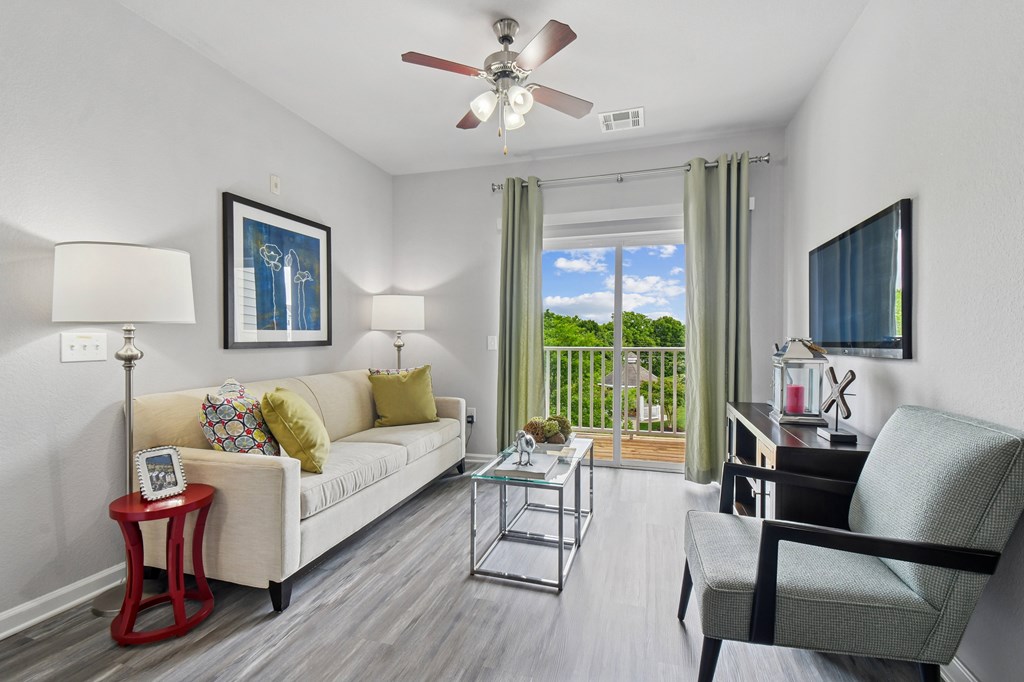 A living room with a white couch, a red side table, and a ceiling fan.