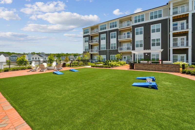 A large grassy area in front of a multi-story apartment building.