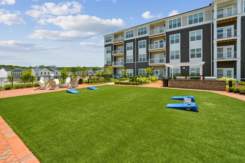 A large grassy area in front of a multi-story apartment building.