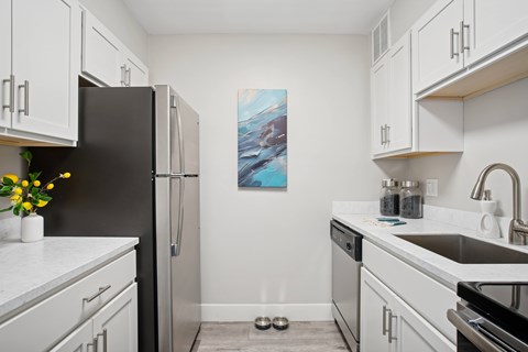 A kitchen with white cabinets and a black fridge.