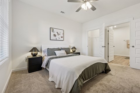 A bedroom with a bed, nightstands, and a ceiling fan.