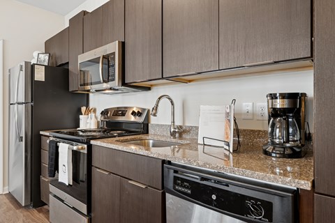 A modern kitchen with dark brown cabinets and stainless steel appliances.