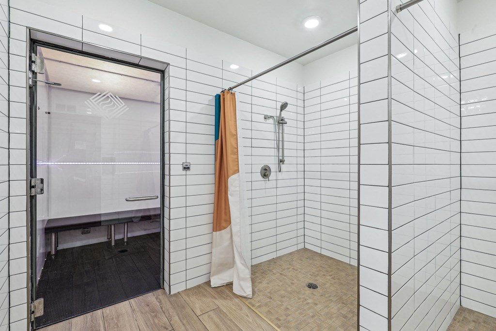 a shower with white tile walls and a sliding glass door
