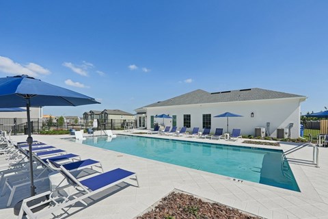 A pool area with sun loungers and a building in the background.