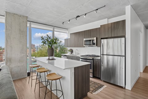 A kitchen with a white counter and stools.