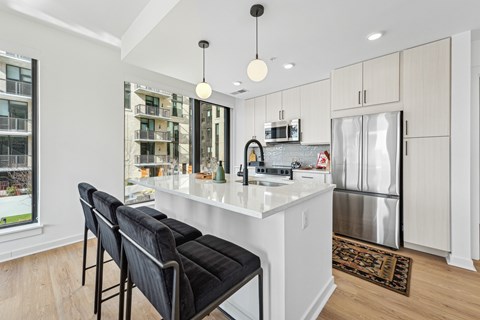 A kitchen with a white counter and black chairs.