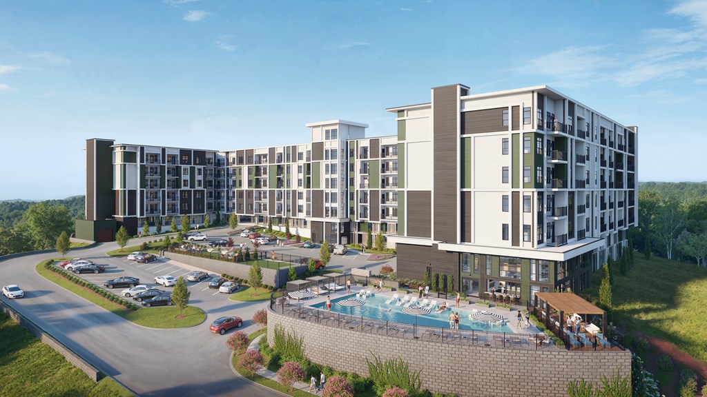 A large hotel with a pool and a parking lot in front.