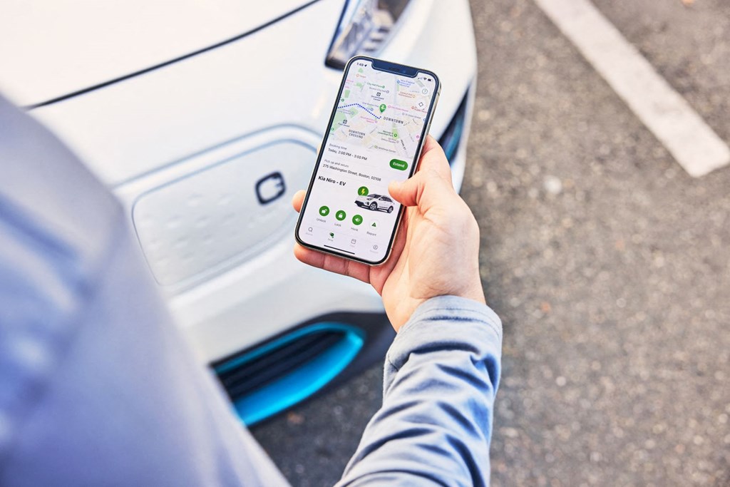 a man holding a cell phone in front of a car