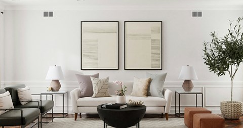 a living room with white furniture and two pictures on the wall