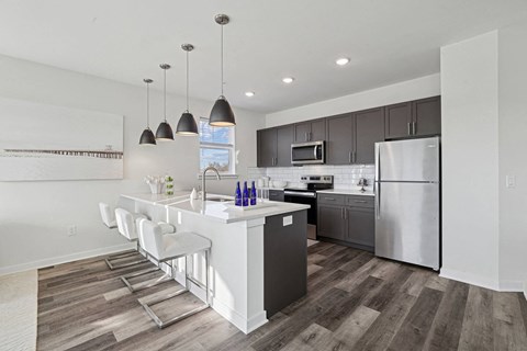 a kitchen with a white island and a stainless steel refrigerator