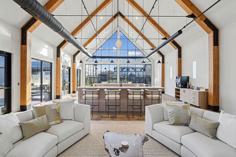 a living room with couches and a kitchen with a large window