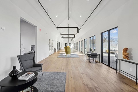 a long hallway with white walls and wood floors and a yellow chair in the middle