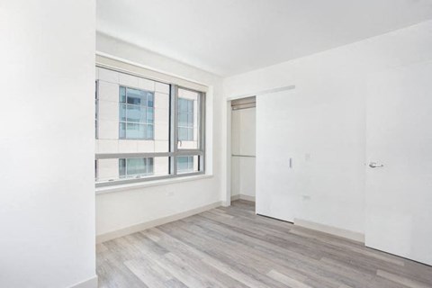 a bedroom with a large window and white walls