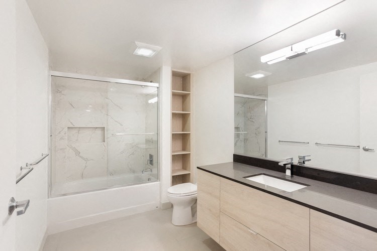 a bathroom with a toilet sink mirror and shower
