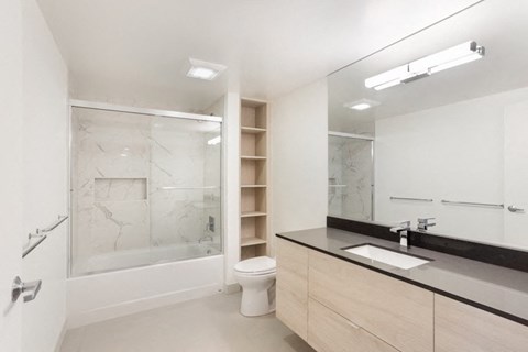 a bathroom with a toilet sink mirror and shower