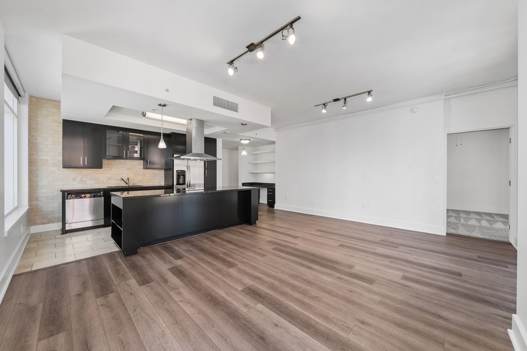 A kitchen with a black countertop and wooden flooring.