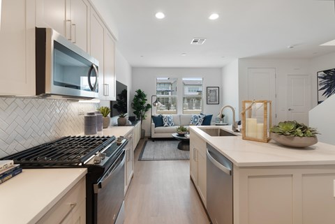 A modern kitchen with a black stove top oven and a white counter top.